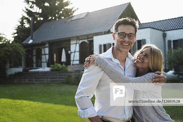 Happy couple embracing in the garden of their country house