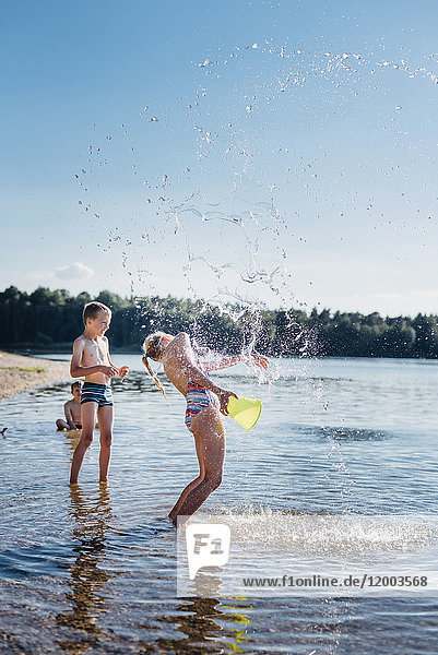 Kinder planschen mit Wasser am Seeufer