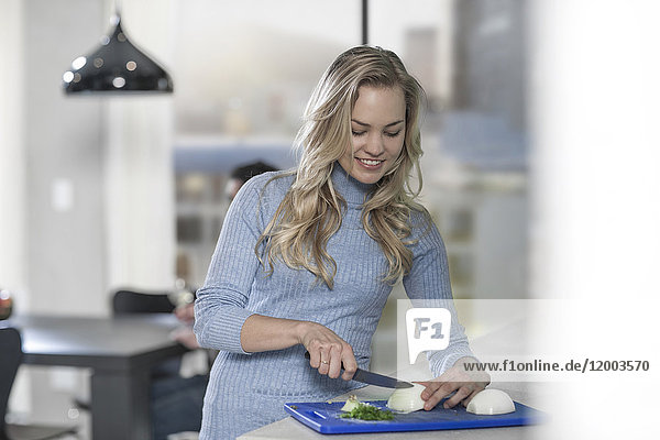 Young woman chopping onions in kitchen