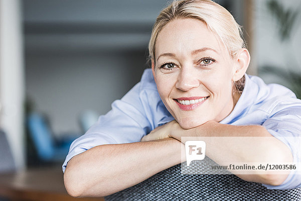 Portrait of smiling businesswoman leaning on chair