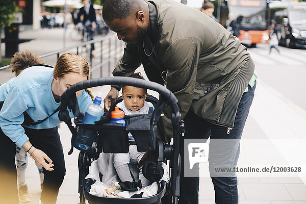 Eltern mit Kleinkind durch Kinderwagen auf dem Bürgersteig in der Stadt