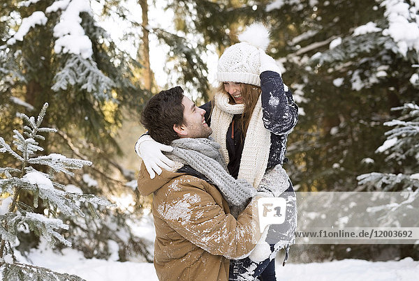 Glückliches junges Paar von Angesicht zu Angesicht im schneebedeckten Winterwald