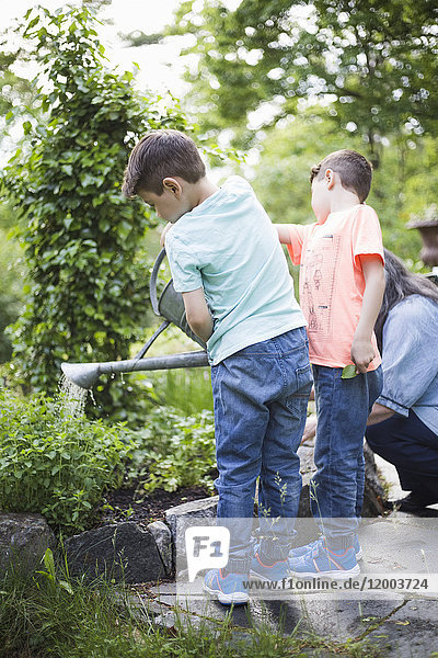 Jungen gießen Pflanzen von Großmutter im Hinterhof