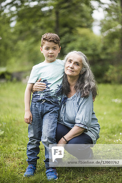 Portrait of grandmother crouching by grandson in back yard