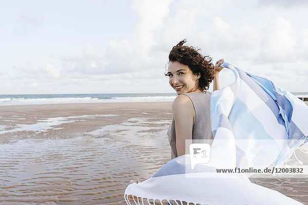 Glückliche Frau mit Tuch am Strand