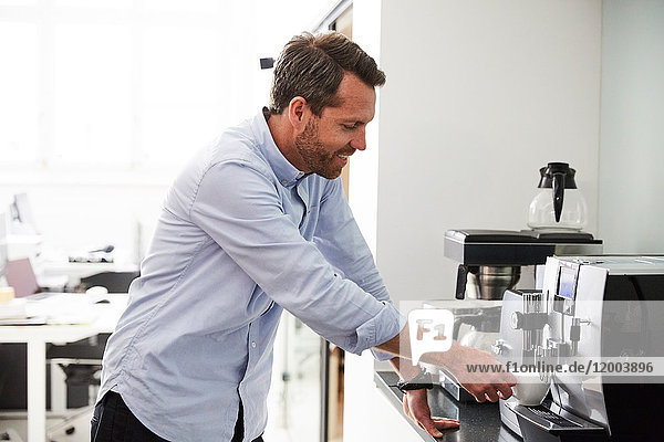 Businessman using coffee maker at kitchen counter in creative office