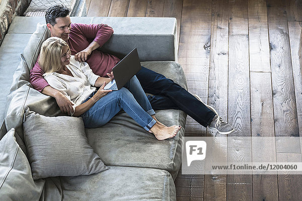 Couple sitting on couch  using laptop