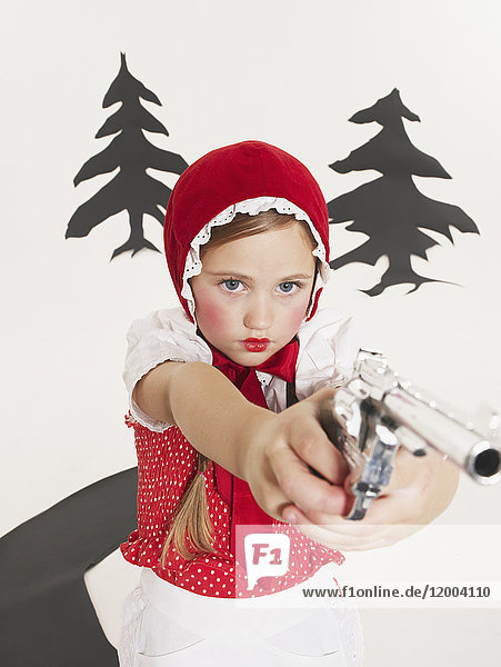 Kleines Mädchen verkleidet als Rotkäppchen mit Pistole