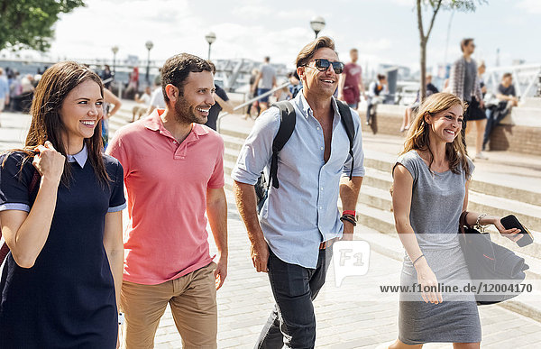 UK  London  Gruppe von Freunden  die am Ufer der Themse spazieren gehen
