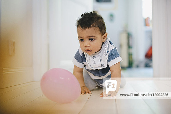 Kleinkind spielt mit dem Ballon  während es zu Hause auf dem Boden krabbelt.