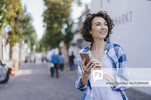 Lächelnde Frau mit Handy in der Stadt