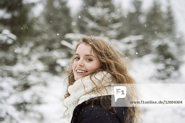 Porträt einer lächelnden jungen Frau im Winterwald