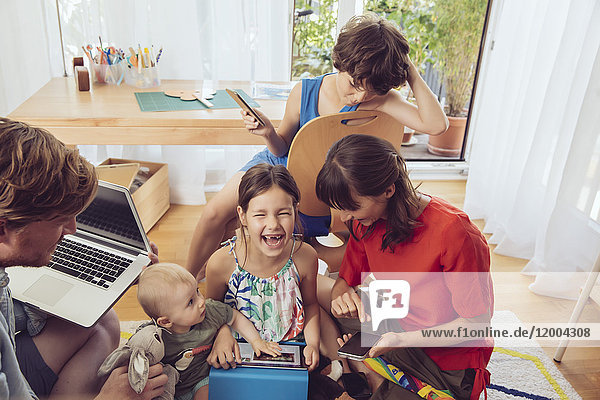 Happy playful family using digital devices in children's room