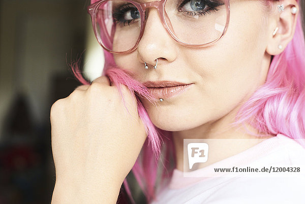 Portrait einer jungen Frau mit rosa Haaren  Brille und Piercings
