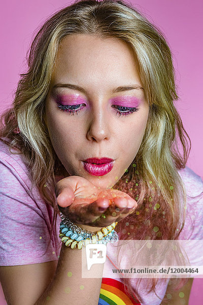 Porträt einer jungen Frau  die vor rosa Hintergrund schimmert.