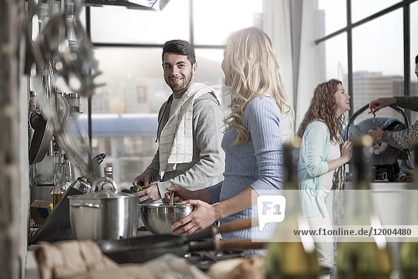 Couple preparing food in kitchen with family in the background