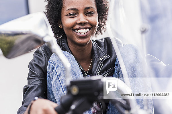 Porträt einer lächelnden jungen Frau mit ihrem Motorrad