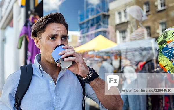 UK  London  Portobello Road  portrait of man drinking coffee in front of a shop window