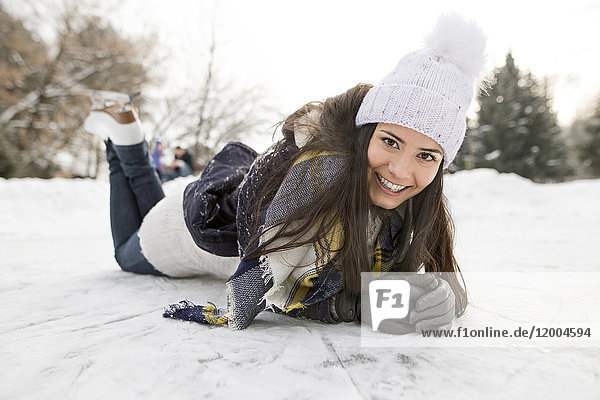 Woman with ice skates lying on snow