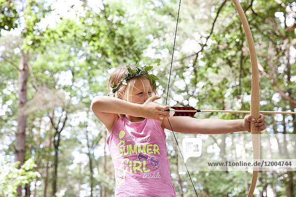 Mädchenschießen mit Pfeil und Bogen im Wald