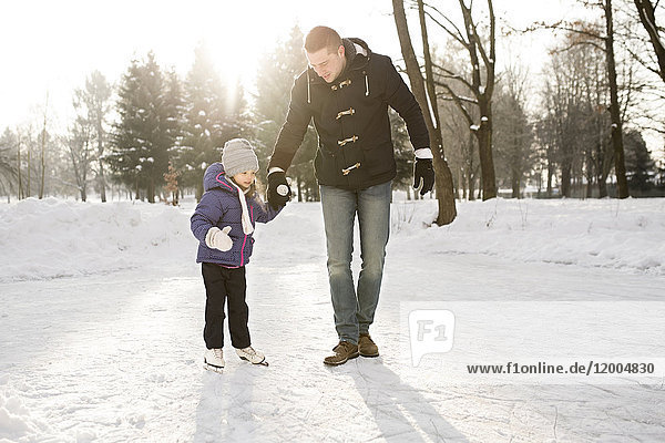 Vater und Tochter Schlittschuhlaufen auf dem zugefrorenen See