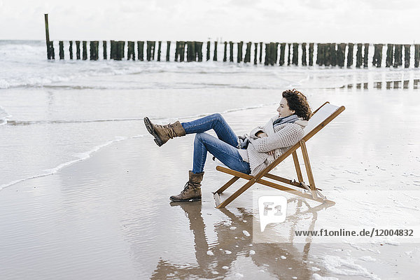 Frau auf Liegestuhl am Strand sitzend