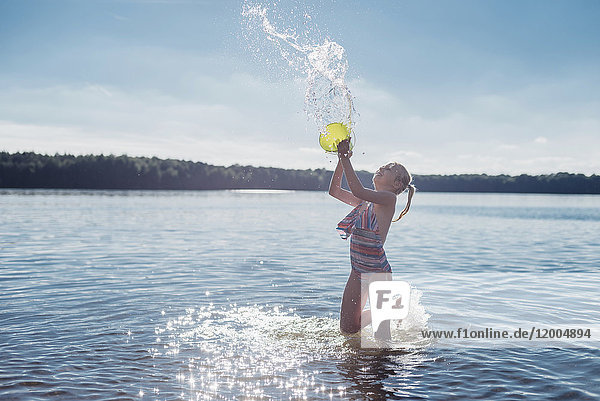 Mädchen spritzt mit Wasser am Seeufer