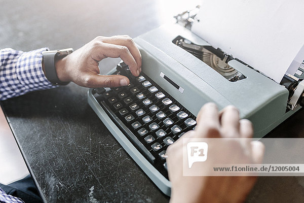 Close-up of man at desk using typewriter