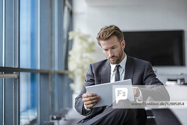 Businessman sitting in conference room using tablet