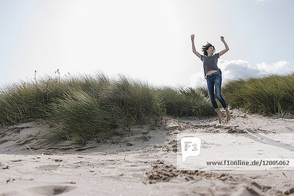 Glückliche Frau beim Springen in der Stranddüne