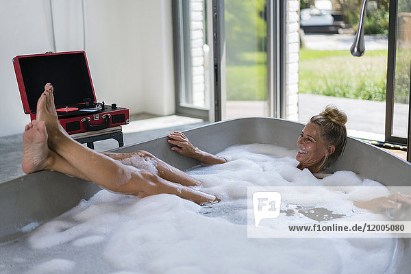 Mature woman taking bubble bath  listening music from analogue record player