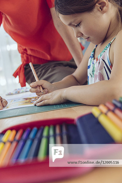 Mother helping girl doing her schoolwork at home