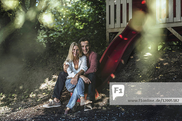 Happy couple sitting on slide of garden shed in the woods