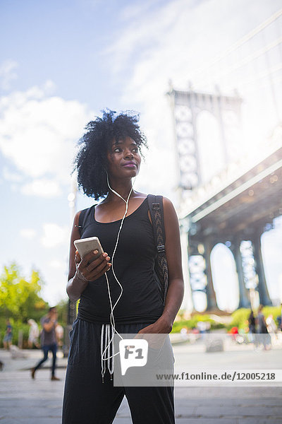 USA  New York City  Brooklyn  Frau beim Musikhören an der Manhattan Bridge