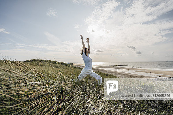 Woman practicing yoga in beach dune