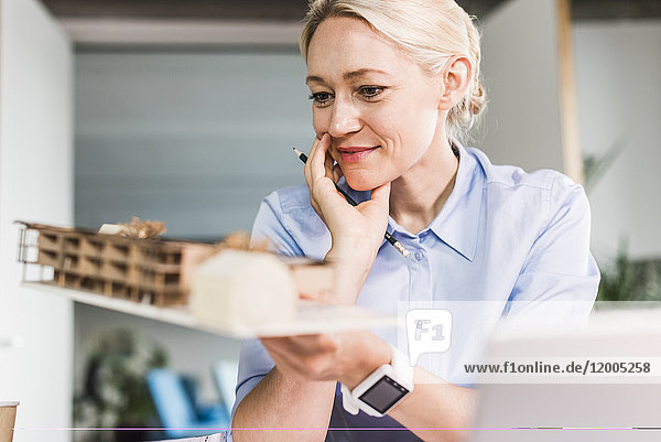 Woman in office holding architectural model