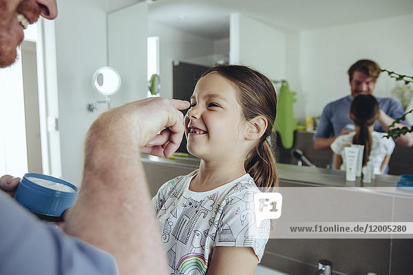 Vater legt Gesichtscreme auf das Gesicht der Tochter