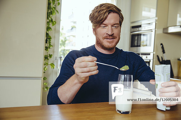Man putting healthy green substance into a glass of milk