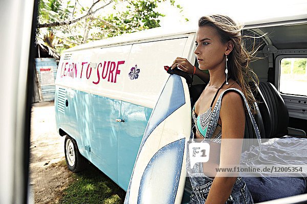 Portrait of woman with surfboard at van