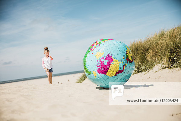 Globus am Strand mit Mädchen im Hintergrund