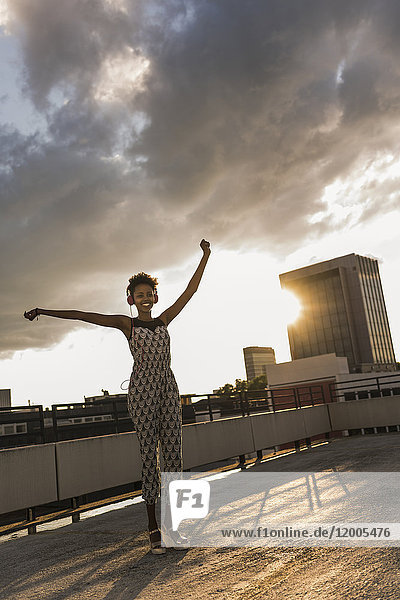 Junge Frau mit Kopfhörer tanzt auf dem Dach