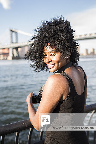 USA  New York City  Brooklyn  portrait of smiling woman standing at the waterfront