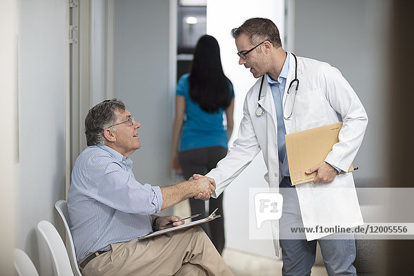 Arzt beim Händeschütteln mit dem Patienten in der Praxis