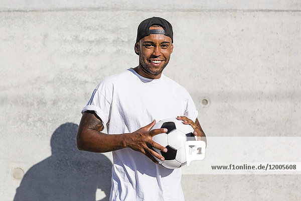 Portrait of smiling young man with soccer ball