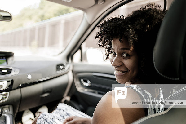 Porträt einer lächelnden jungen Frau im Auto