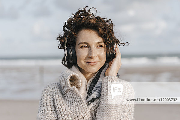 Lächelnde Frau am Strand mit Kopfhörer