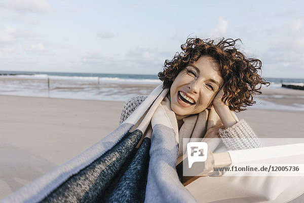 Porträt der glücklichen Frau im Liegestuhl am Strand