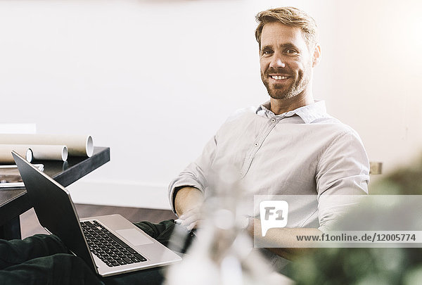Porträt eines lächelnden Architekten mit Laptop in seinem Büro