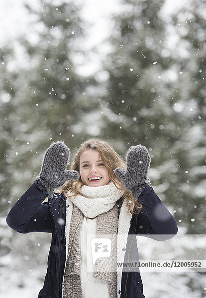 Porträt der glücklichen jungen Frau bei Schneefall in der Natur