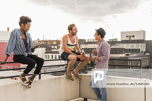 Three friends socializing on a rooftop party